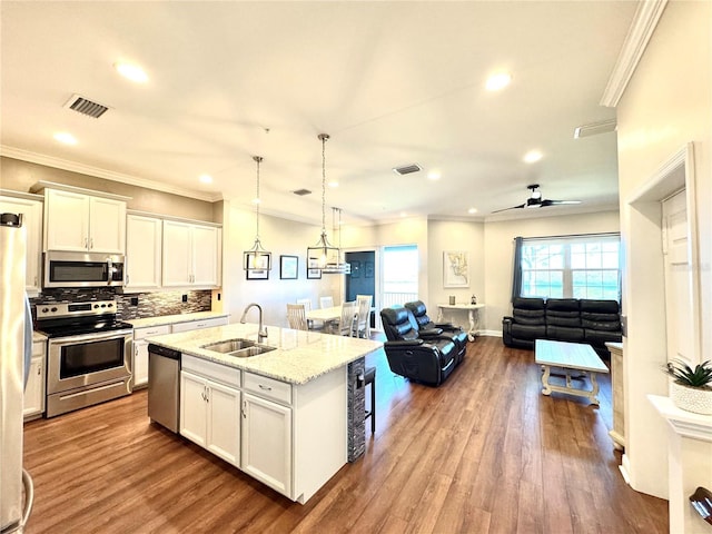 kitchen with white cabinets, sink, stainless steel appliances, and a center island with sink