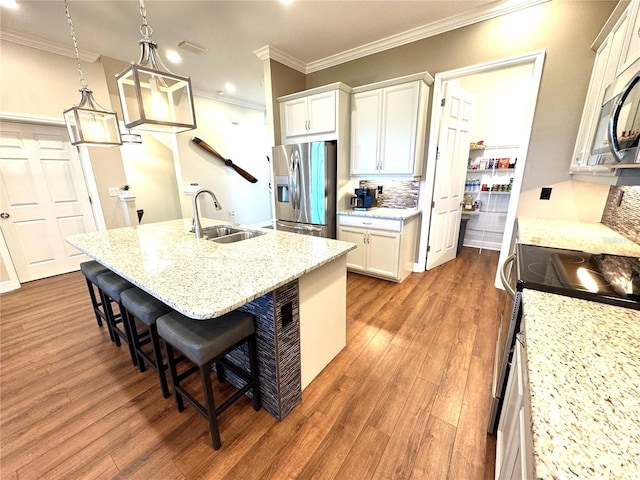 kitchen featuring appliances with stainless steel finishes, sink, a center island with sink, decorative light fixtures, and white cabinets