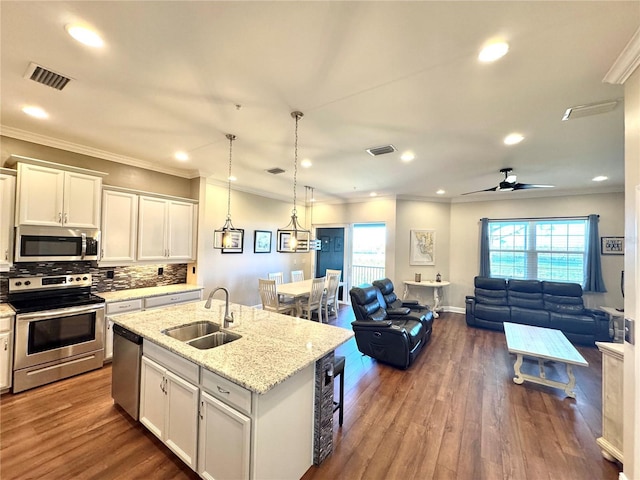 kitchen featuring appliances with stainless steel finishes, a kitchen island with sink, sink, white cabinets, and hanging light fixtures