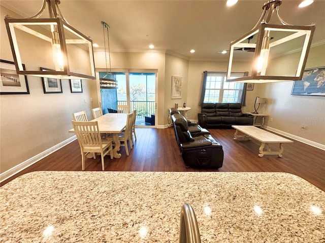 kitchen featuring pendant lighting, dark wood-type flooring, light stone counters, and ornamental molding