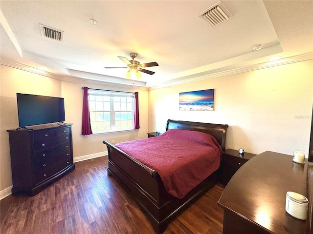 bedroom with ornamental molding, a tray ceiling, ceiling fan, and dark wood-type flooring