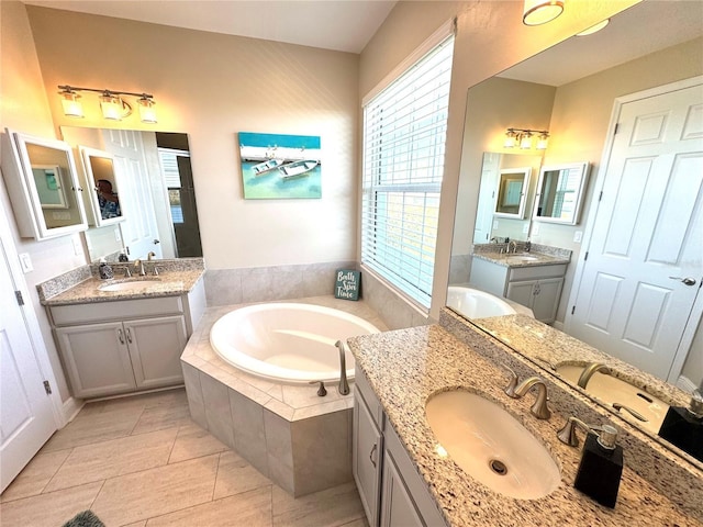 bathroom featuring vanity, tile patterned floors, plenty of natural light, and tiled tub