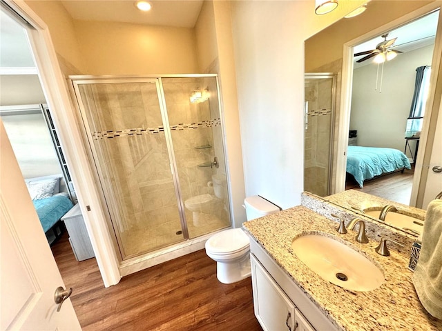 bathroom with walk in shower, hardwood / wood-style floors, vanity, and toilet