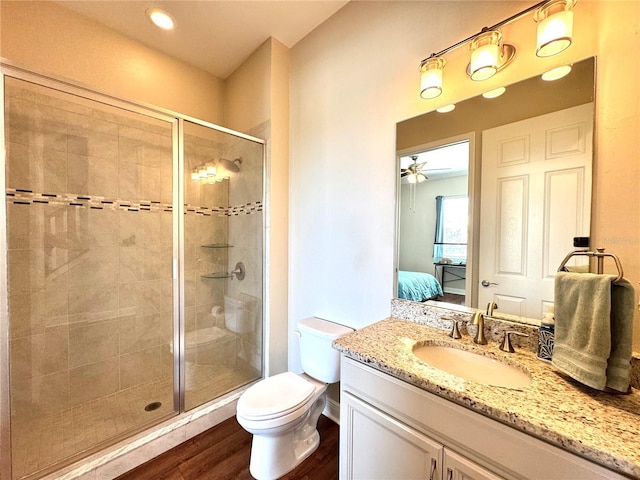 bathroom with ceiling fan, hardwood / wood-style floors, toilet, a shower with door, and vanity