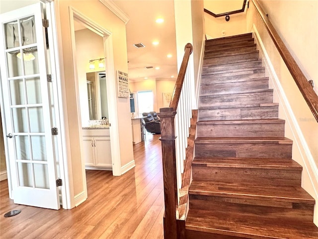 stairway with hardwood / wood-style floors and ornamental molding