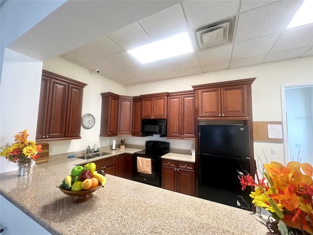 kitchen with black appliances, a paneled ceiling, kitchen peninsula, and sink