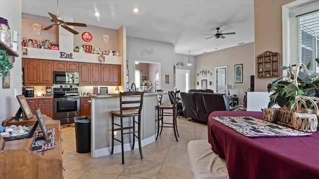 kitchen with a towering ceiling, a breakfast bar, plenty of natural light, and stainless steel range with electric stovetop