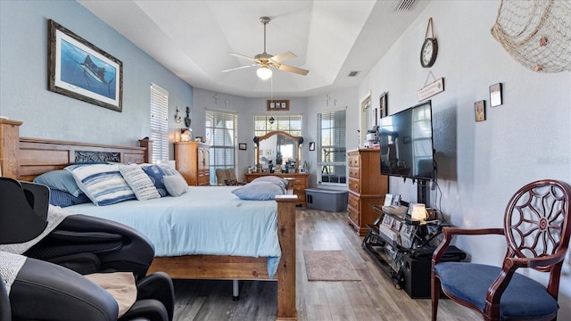 bedroom with ceiling fan, hardwood / wood-style floors, and a tray ceiling