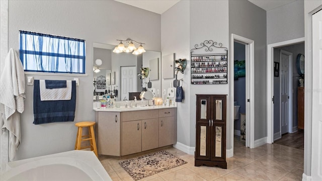 bathroom with a tub to relax in, vanity, and tile patterned flooring