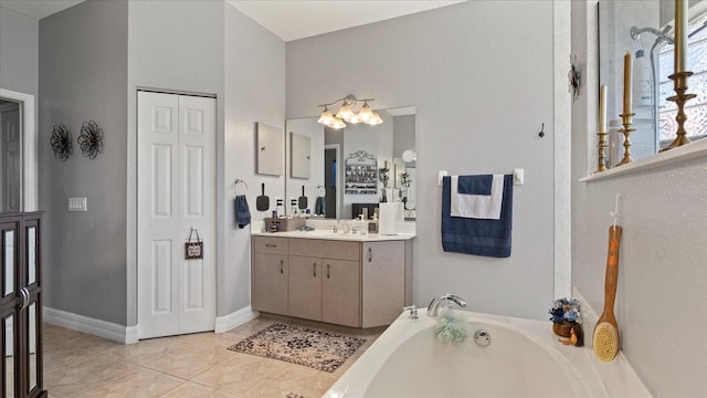 bathroom with tile patterned floors, a washtub, and vanity