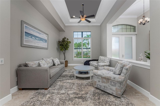 living room with ornamental molding, ceiling fan with notable chandelier, and a raised ceiling