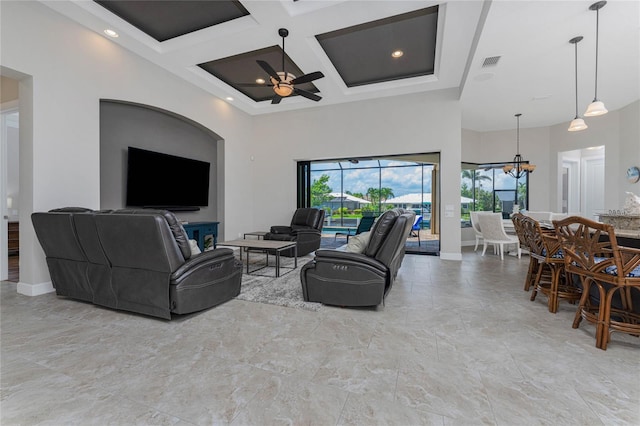 living room with ceiling fan with notable chandelier, beam ceiling, a towering ceiling, and coffered ceiling