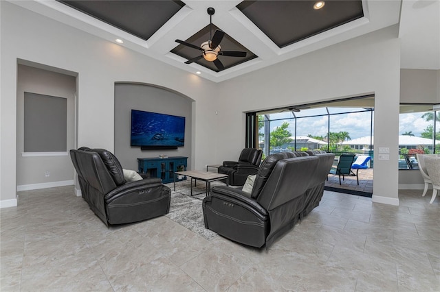 living room with ceiling fan, a high ceiling, beam ceiling, and coffered ceiling