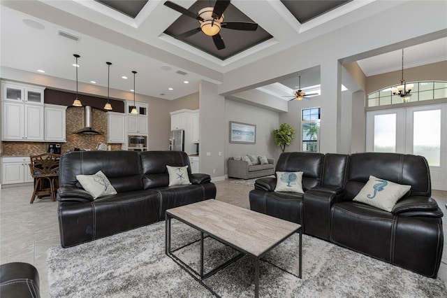 living room with ceiling fan with notable chandelier, a high ceiling, crown molding, and coffered ceiling