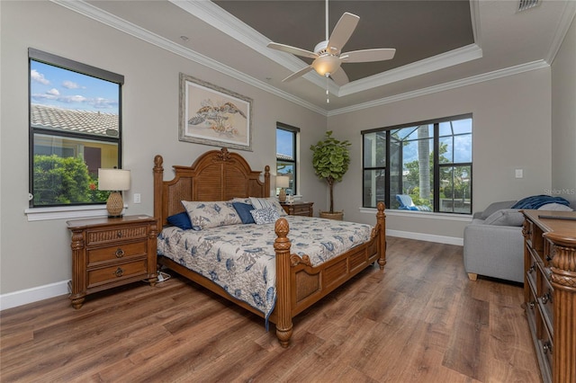 bedroom featuring ceiling fan, a tray ceiling, dark hardwood / wood-style flooring, and ornamental molding