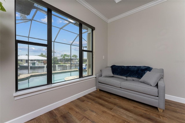 living area with dark wood-type flooring, a wealth of natural light, ornamental molding, and a water view