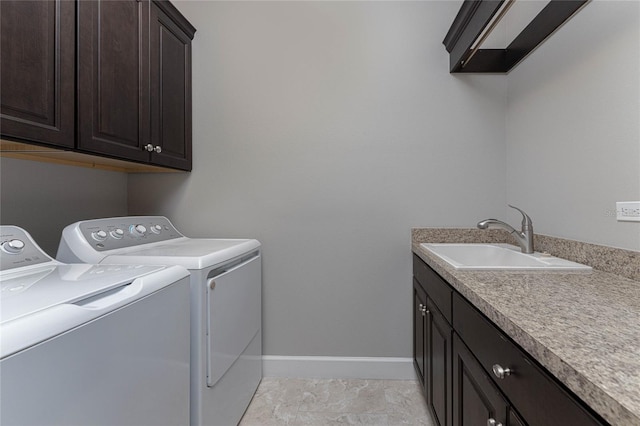 laundry area featuring sink, washing machine and clothes dryer, and cabinets