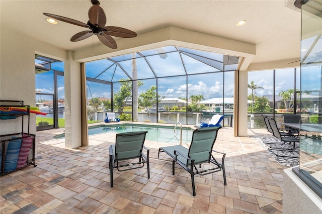 view of patio featuring a water view, ceiling fan, and a lanai