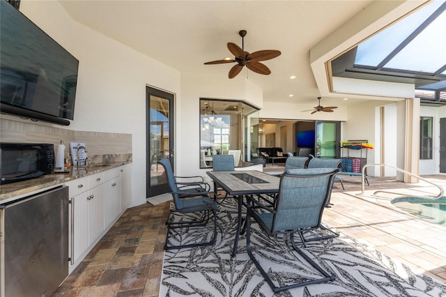 view of patio with ceiling fan, an outdoor kitchen, and a swimming pool