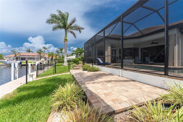 view of patio / terrace featuring ceiling fan, a lanai, a boat dock, and a water view