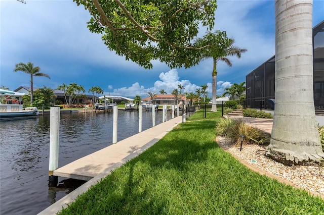 dock area featuring glass enclosure, a water view, and a lawn