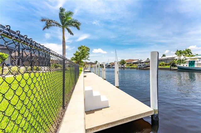 view of dock with a lawn and a water view