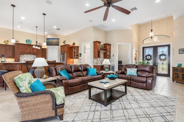 living room with ceiling fan, a towering ceiling, light tile patterned floors, and french doors