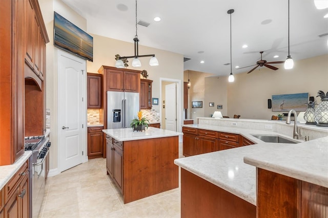 kitchen with sink, hanging light fixtures, ceiling fan, appliances with stainless steel finishes, and a kitchen island