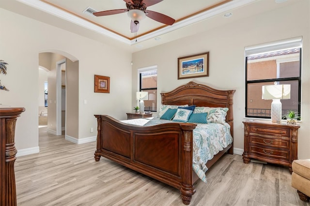 bedroom with ensuite bathroom, a tray ceiling, ceiling fan, crown molding, and light hardwood / wood-style floors