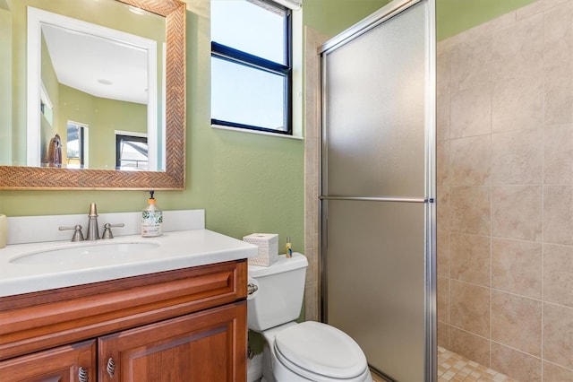 bathroom with a shower with door, vanity, plenty of natural light, and toilet