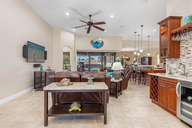 tiled living room with wine cooler, ceiling fan, and sink