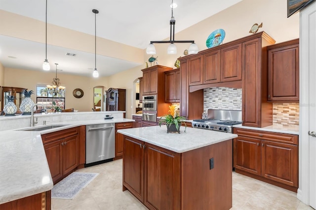 kitchen featuring sink, hanging light fixtures, stainless steel appliances, decorative backsplash, and a kitchen island