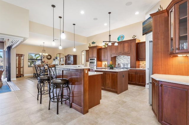 kitchen featuring pendant lighting, a center island, an inviting chandelier, decorative backsplash, and a kitchen bar