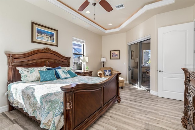 bedroom with ceiling fan, light hardwood / wood-style floors, access to exterior, and a tray ceiling