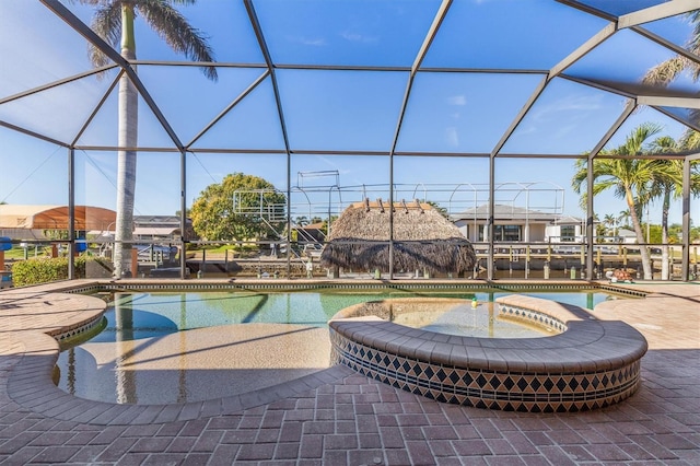 view of pool with an in ground hot tub, a patio, and glass enclosure