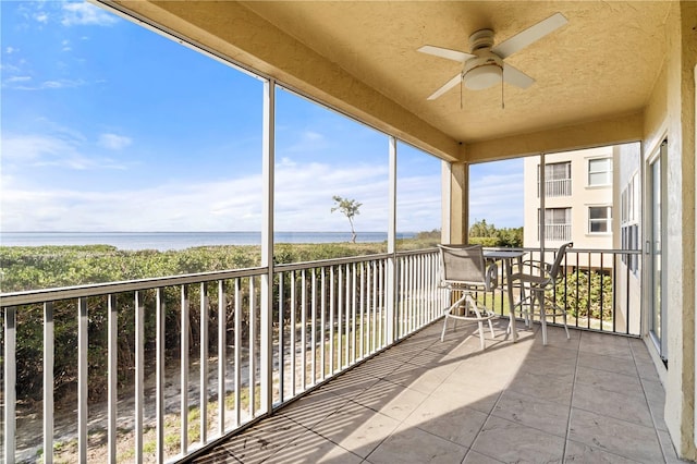 unfurnished sunroom featuring a water view and ceiling fan