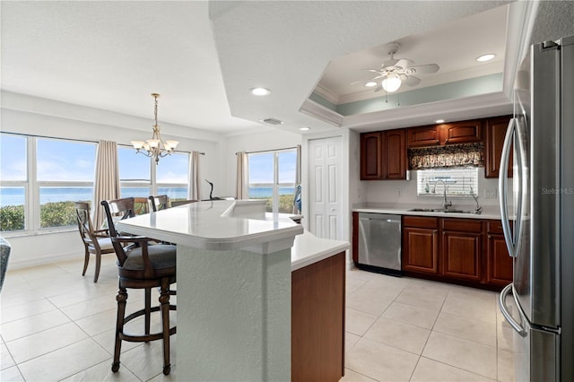 kitchen with pendant lighting, a water view, crown molding, sink, and stainless steel appliances