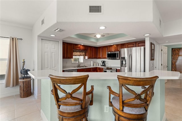 kitchen featuring ornamental molding, stainless steel appliances, a raised ceiling, sink, and light tile patterned floors