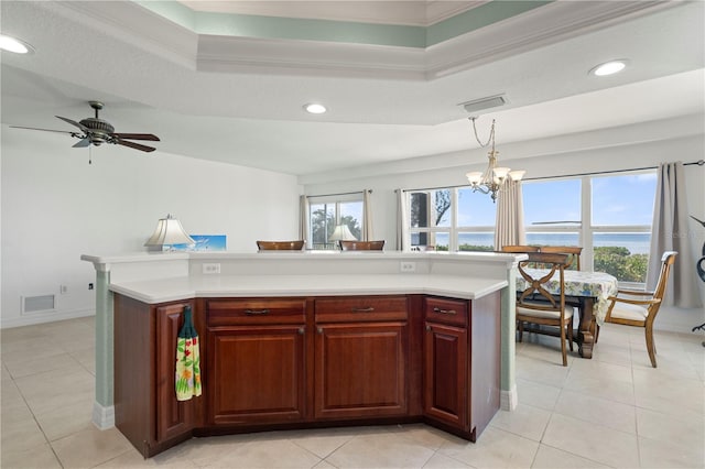 kitchen with a center island, a raised ceiling, decorative light fixtures, a water view, and ceiling fan with notable chandelier