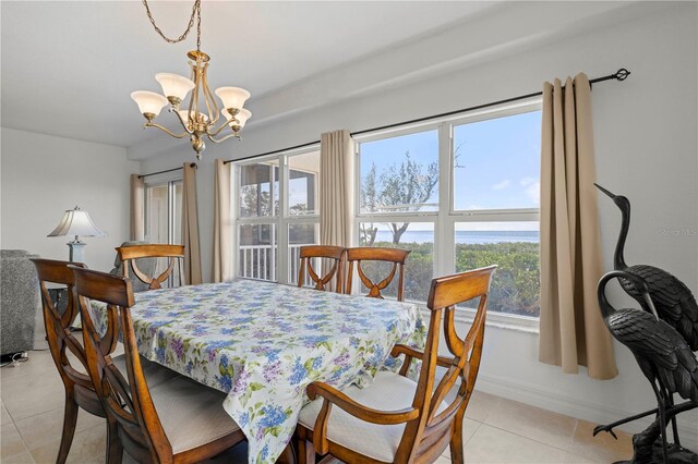 tiled dining area featuring a chandelier and a water view