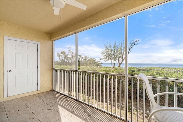 unfurnished sunroom with ceiling fan and a water view