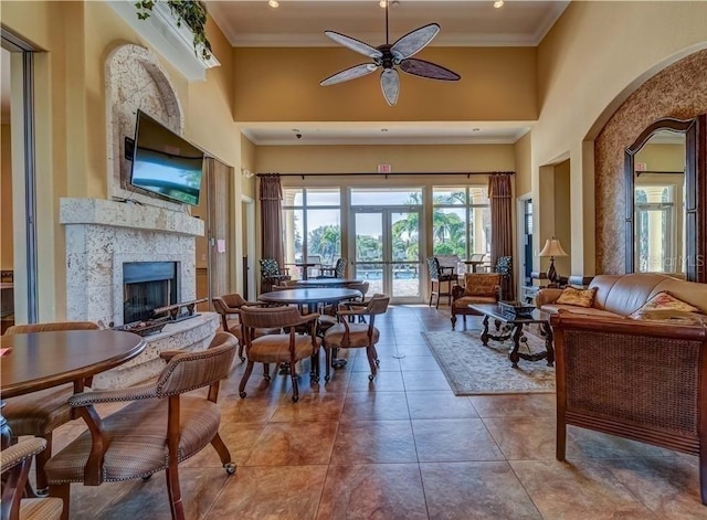 tiled living room featuring a high ceiling, french doors, crown molding, ceiling fan, and a fireplace