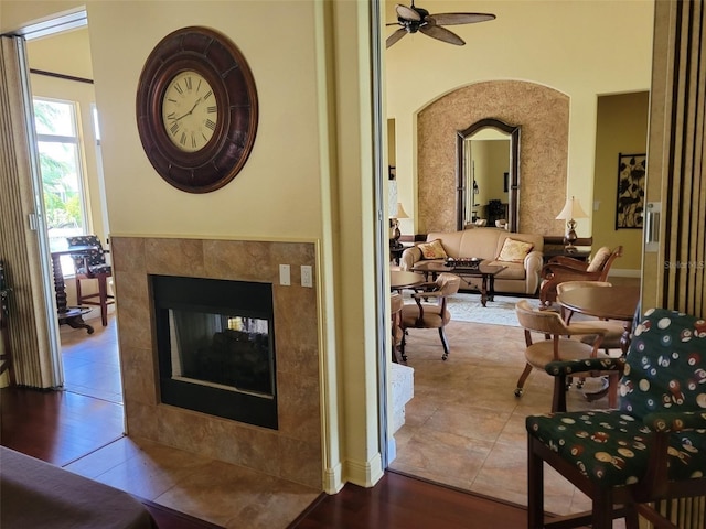 living room featuring wood-type flooring, ceiling fan, and a tiled fireplace