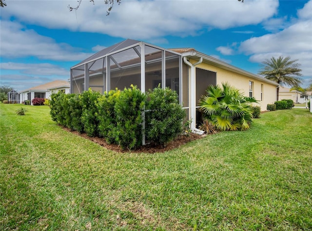 view of side of property with a yard and a lanai