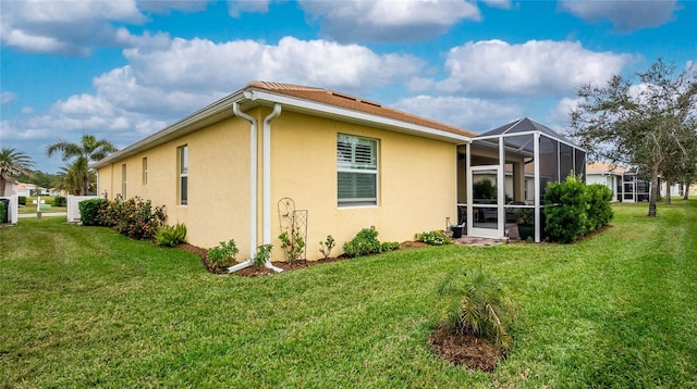 view of side of property featuring a lawn and glass enclosure