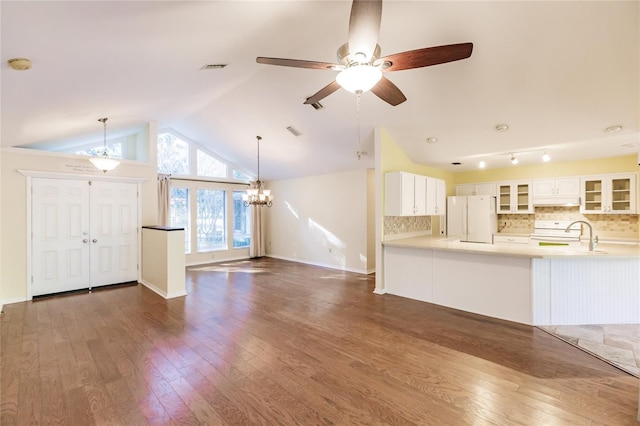 unfurnished living room with ceiling fan with notable chandelier, dark wood-type flooring, and vaulted ceiling