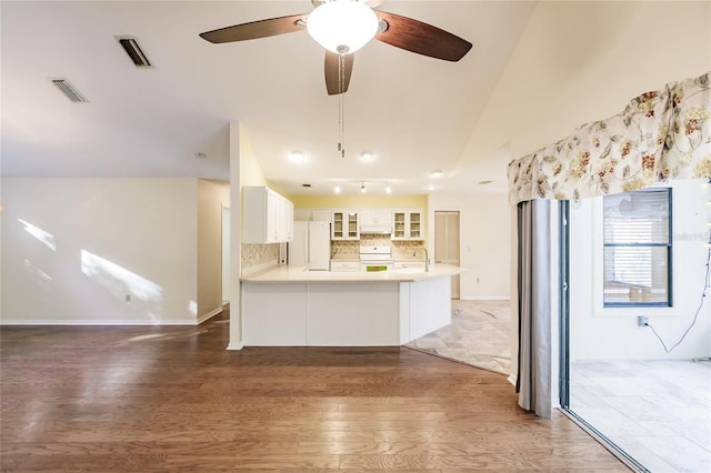 kitchen with dark hardwood / wood-style flooring, kitchen peninsula, stove, white fridge, and white cabinets