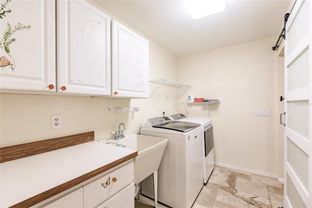 laundry room featuring a barn door, sink, cabinets, and washing machine and dryer