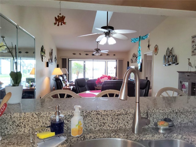 kitchen featuring lofted ceiling, sink, and light stone countertops