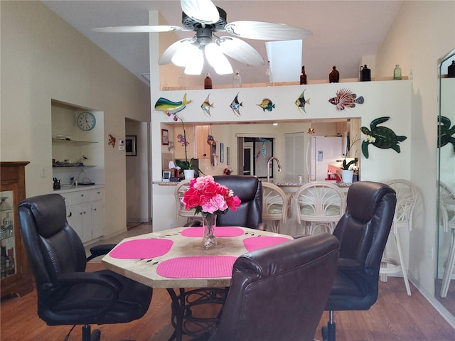 dining room with ceiling fan, light hardwood / wood-style flooring, and vaulted ceiling